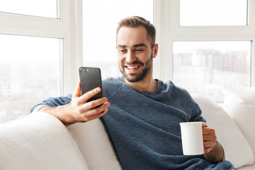 Person sitting on a sofa with cell phone in hand